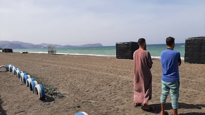 Los hermanos Usama y Mohamed, en una playa de la bahía de Alhucemas desde donde partió su hermano menor, Marwan, hacia España. Al fondo se encuentra el peñón de Alhucemas, con una base militar española.