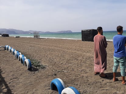 Los hermanos Usama y Mohamed, en una playa de la bahía de Alhucemas desde donde partió su hermano menor, Marwan, hacia España. Al fondo se encuentra el peñón de Alhucemas, con una base militar española.