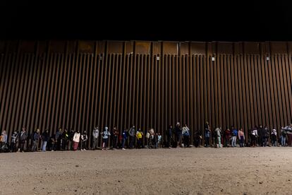 Un grupo de inmigrantes esperan en la valla fronteriza con México en Yuma, Arizona (EE UU) antes de ser trasladados a un centro de acogida el 29 de octubre de 2022.