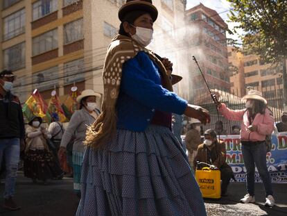 Una mujer rocía desinfectante a manifestantes en medio de la pandemia COVID-19, durante una marcha pidiendo acceso gratuito a internet y computadoras al gobierno, para que sus hijos puedan tomar clases en línea, en La Paz, Bolivia.