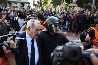 Ernest Maragall escoltado por los Mossos d'Esquadre durante la concentración de indignados las puertas del Parque de la Ciutadella de Barcelona.