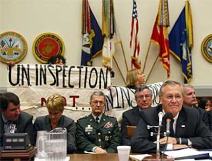 Varias personas protestan contra la política de Bush en Irak durante la comparecencia de Rumsfeld ante un comité. PLANO MEDIO - ESCENA