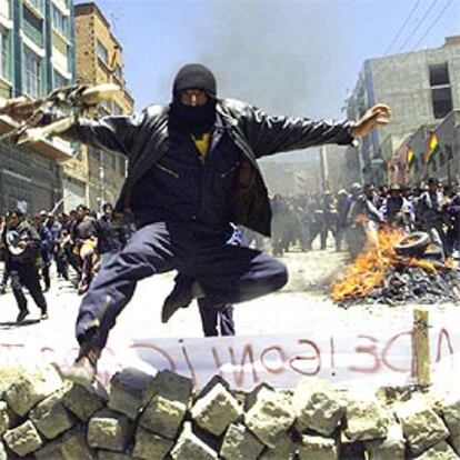 Un manifestante encapuchado salta una barricada en La Paz.