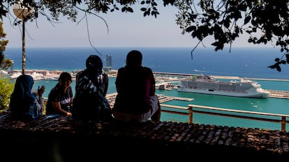 Varias personas conversan en un mirador con un crucero al fondo, en el puerto de Barcelona.