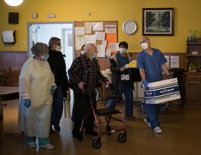 Personal de la residencia acompaña a una anciano tras la campaña de vacunas en el centro.