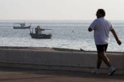 Un hombre camina frente a algunos pesqueros de la Línea de la Concepción que faenan en la zona de levante.