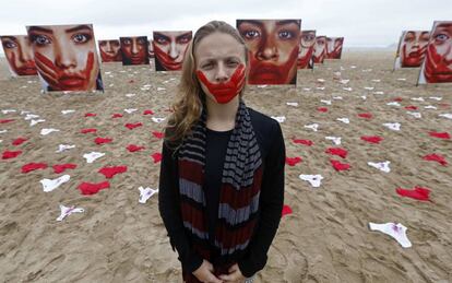 Una voluntaria de la ONG Río de Paz posa en la playa de Copacabana, junto a imágenes de modelos que representan a mujeres que sufrieron algún tipo de abuso sexual.