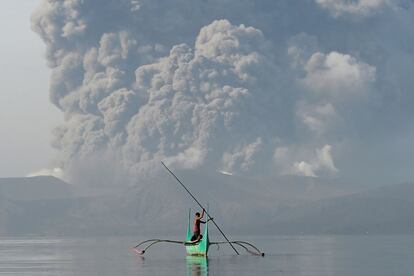 Un joven que vive al pie del volcán Taal monta una canoa mientras el volcán arroja cenizas como se ve desde la ciudad de Tanauan, al sur de Manila, el 13 de enero.