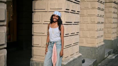 Una chica con bandana en la cabeza y otra enganchada en el pantalón posando para una foto.