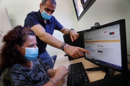 Un voluntario de Cáritas ayuda a una usuaria a hacer un trámite en línea.