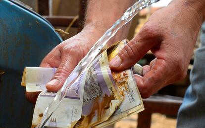 Un hombre lava billetes llenos de barro después de la tormenta. La economía de la ciudad ha quedado paralizada durante toda la semana.