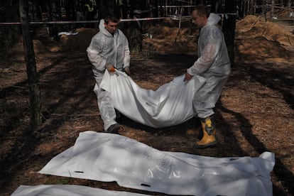 Operarios trasladan cuerpo de una de las fosas comunes de Izium, el sábado. 