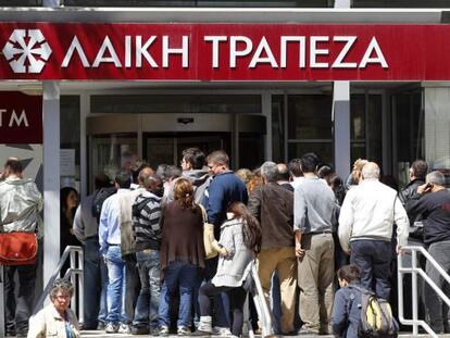 Gente ante una sucursal del Laiki esperan a que el banco reabra sus puertas, este jueves en Nicosia.