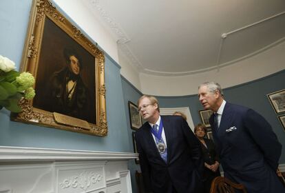 El alcalde de Londres, David Wootton, y el príncipe Carlos de Inglaterra, observando el retrato de Dickens durante la visita al Museo Charles Dickens de Londres, en el bicentenario del nacimiento del escritor.