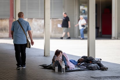Una pareja de personas sin hogar (sin techo) duermen junto al Mercado de Sant Antoni, en Barcelona.