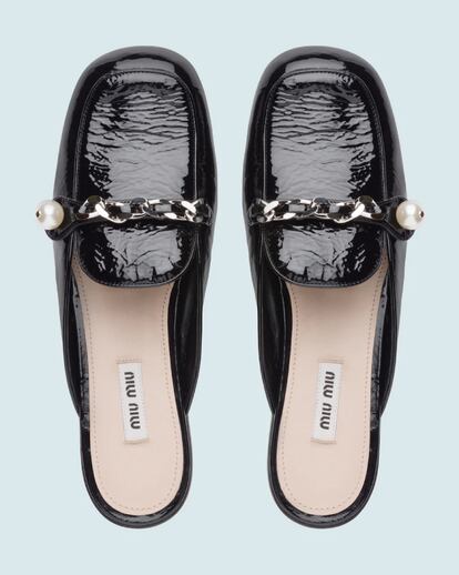 Miu Miu.
Trastocar por completo un calzado de toda la vida como el mocasín es una de proezas que solo podría hacer la segunda marca de Miuccia Prada. Sobre piel acharolada elimina cualquier cierre exterior para transformarlo en una cómoda (y elegante) babucha, al incluir en la hebilla perlas y una cadena de oro.