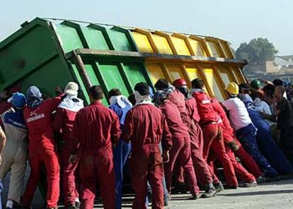 Un grupo de trabajadores vuelca un contenedor en las protestas de la factoría de astilleros en Sevilla.