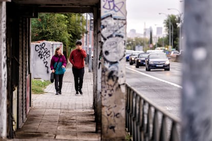 Dos personas pasean por una acera estrecha y en mal estado en el paseo de Extremadura de Madrid, junto a seis carriles de coches.