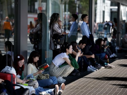 Varias personas esperan en la calle en la tarde de este lunes.