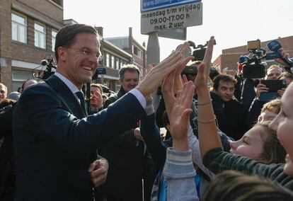 El primer ministro holandés, Mark Rutte, saluda a un grupo de niños antes de depositar su voto, en La Haya.