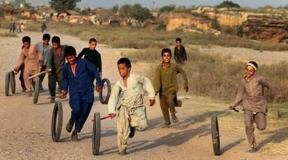 Niños afganos refugiados juegan con neumáticos en Islamabad, Pakistán.