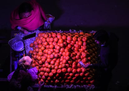 Una mujer india compra naranjas a un vendedor de carretera, en Nueva Delhi.