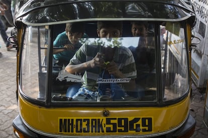 Tres niños juegan dentro de un tuk-tuk, el popular taxi de tres ruedas.