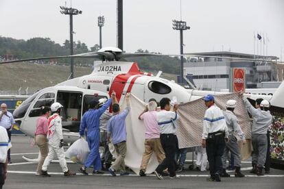 Treballadors del circuit eviten que es vegi com De Angelis és evacuat del circuit en helicòpter.