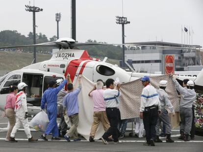 Treballadors del circuit eviten que es vegi com De Angelis és evacuat del circuit en helicòpter.