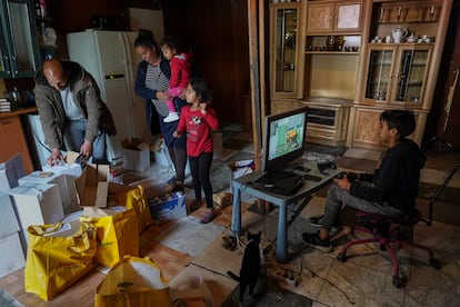 Ángel Manzano (12 años, a la derecha), se entretiene en la chabola con un videojuego delante de su hermana Mireia (7) y sus padres, Jorge (41) y María (44), que sostiene a su nieta Naiara (3).