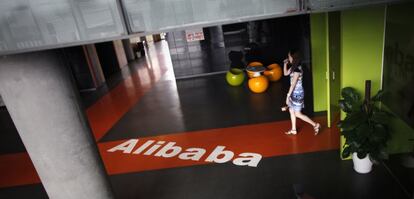 Una empleada pasa junto al logo de Alibaba en la sede de la empresa en Hangzhou (China).