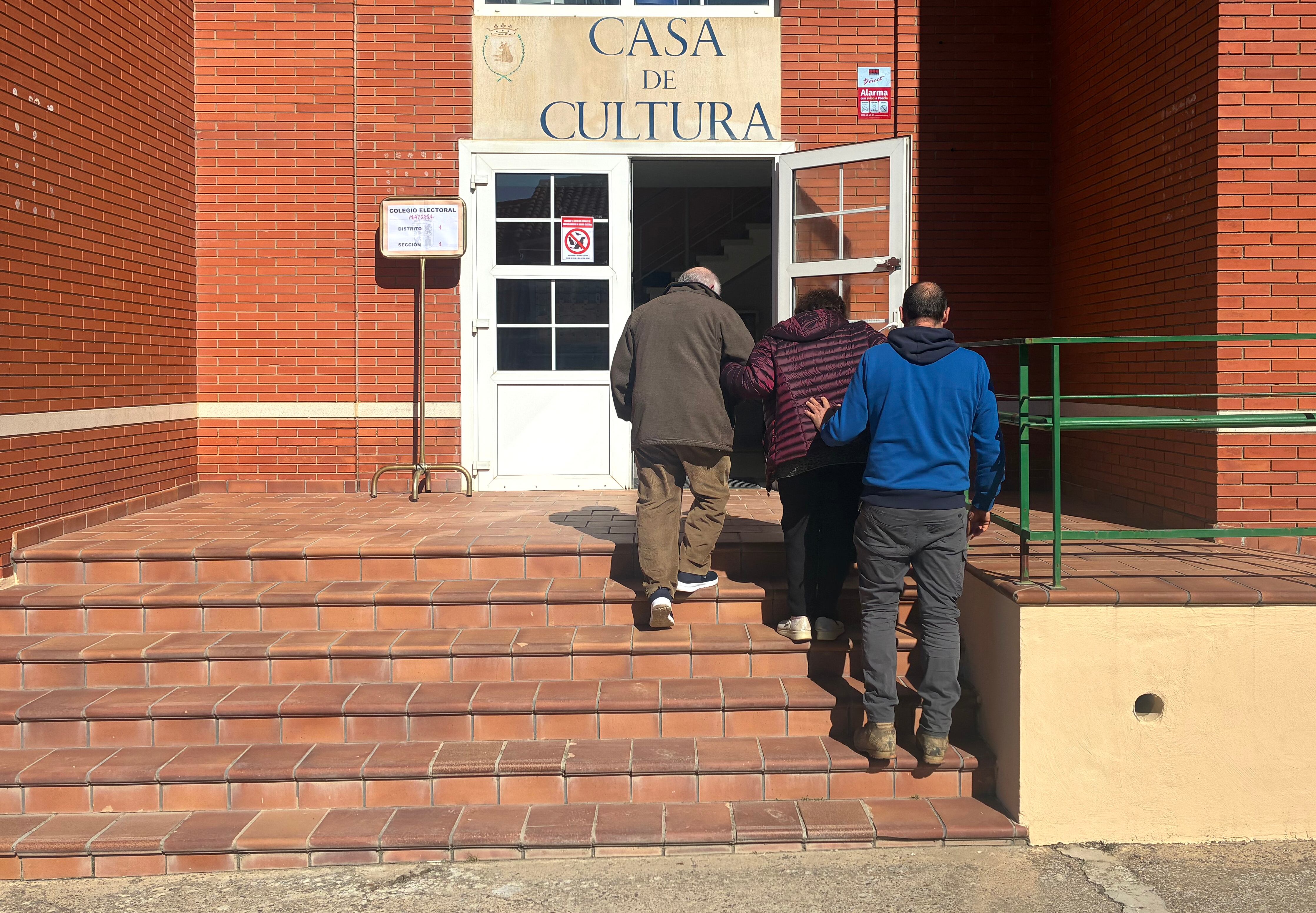 Unos ancianos, ayudados por su hijo, acceden al colegio electoral de Mayorga de Campos (Valladolid)