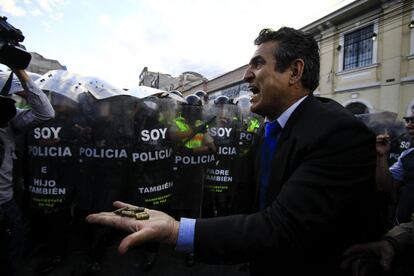 Un manifestante sostiene balas frente a una línea de policías durante una manifestación, en Quito (Ecuador). La policía de Ecuador se enfrento y disolvió una concentración de grupos de oposición, tras registrarse incidentes en las inmediaciones de la Asamblea Nacional, que hoy aprobó unas polémicas enmiendas a la Constitución impulsadas por el Gobierno.