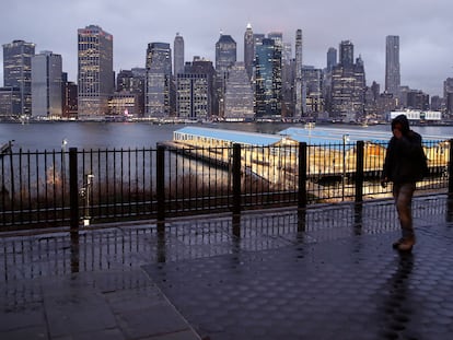 Homem caminha por uma rua deserta diante dos prédios de Manhattan.