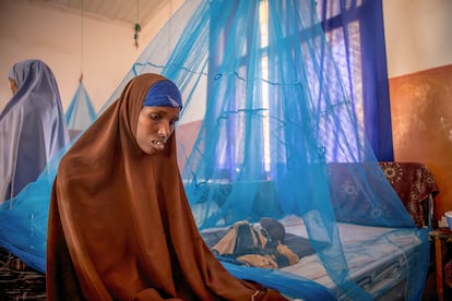 Una madre sentada junto a su hijo de dos años, ingresado en un hospital de Baidoa, en Somalia, con síntomas de desnutrición.