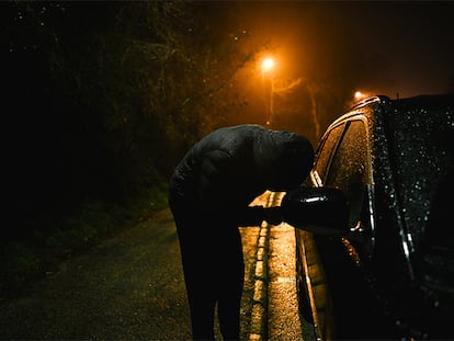 Una persona intentando robar un coche por la noche.