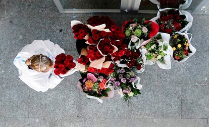 Una mujer con traje protector junto a varios ramos de flores en una de las puertas del hospital provisional instalado en Ifema (Madrid).