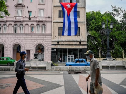 Un hombre camina por la calle al lado de un agente de policía en el paseo de El Prado en La Habana este 15 de noviembre.