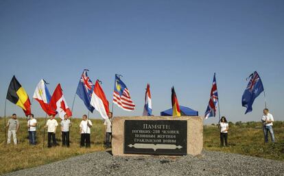 Varias personas sostienen banderas en se&ntilde;al de homenaje a las nacionalidades de las v&iacute;ctimas del vuelo MH17, este viernes en Ucrania.