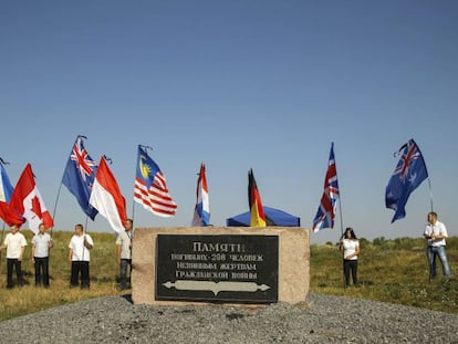 Varias personas sostienen banderas en se&ntilde;al de homenaje a las nacionalidades de las v&iacute;ctimas del vuelo MH17, este viernes en Ucrania.