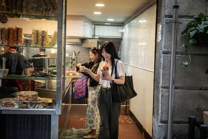 Los turistas coreanos compran churros con chocolate en la Churrería San Román de Barcelona. En la imagen Nayouny y Soomin, estudiantes de Seúl.