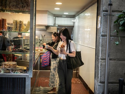 Los turistas coreanos compran churros con chocolate en la Churrería San Román de Barcelona. En la imagen Nayouny y Soomin, estudiantes de Seúl.