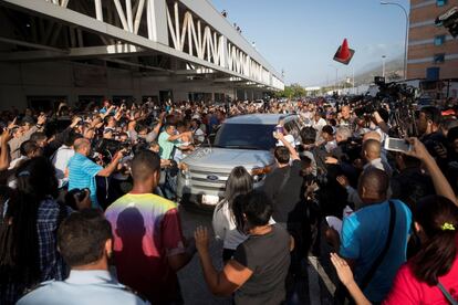 Juan Guaidó y su esposa, Fabiana Rosales, salen en un automóvil privado del aeropuerto de Caracas en medio de una multitud de simpatizantes y opositores.