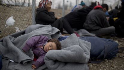 Un niño duerme junto a unos refugiados en la frontera entre Grecia y Macedonia.