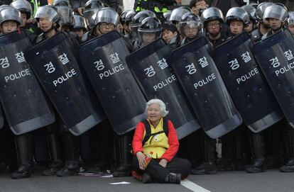 Una mujer se sienta delante de la policía antidisturbios que bloquean el camino a los manifestantes durante la protesta contra el gobierno de Seúl, Corea del Sur.