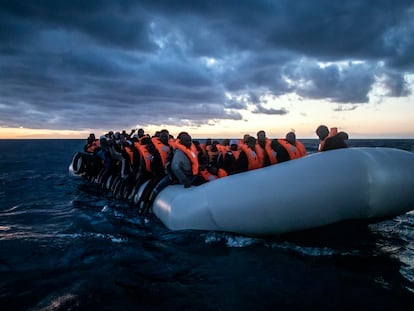 Migrantes y refugiados de diferentes nacionalidades africanas esperan ayuda a bordo de una embarcación de goma abarrotada en el mar Mediterráneo