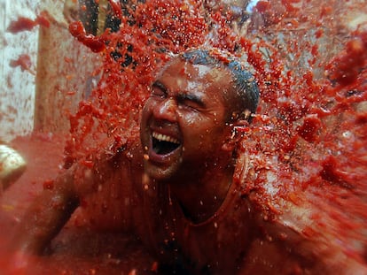 Un participante recibe una explosión de zumo de tomate sobre su cuerpo durante la fiesta de la Tomatina de Buñol.