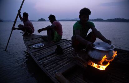 Pescadores indios preparan comida en una barca de pesca en el río Brahmaputra en Gauhati (India).