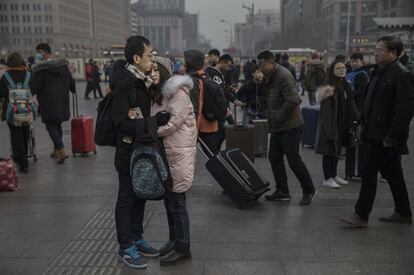 Una pareja china se abraza frente a la estación de tren de Pekín.