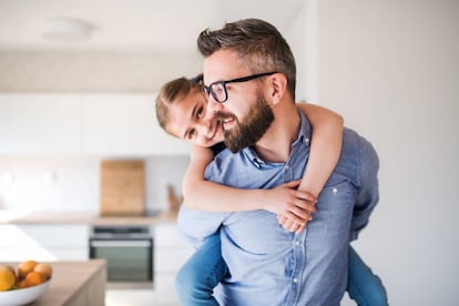 Un padre lleva a hombros a su hija en casa.